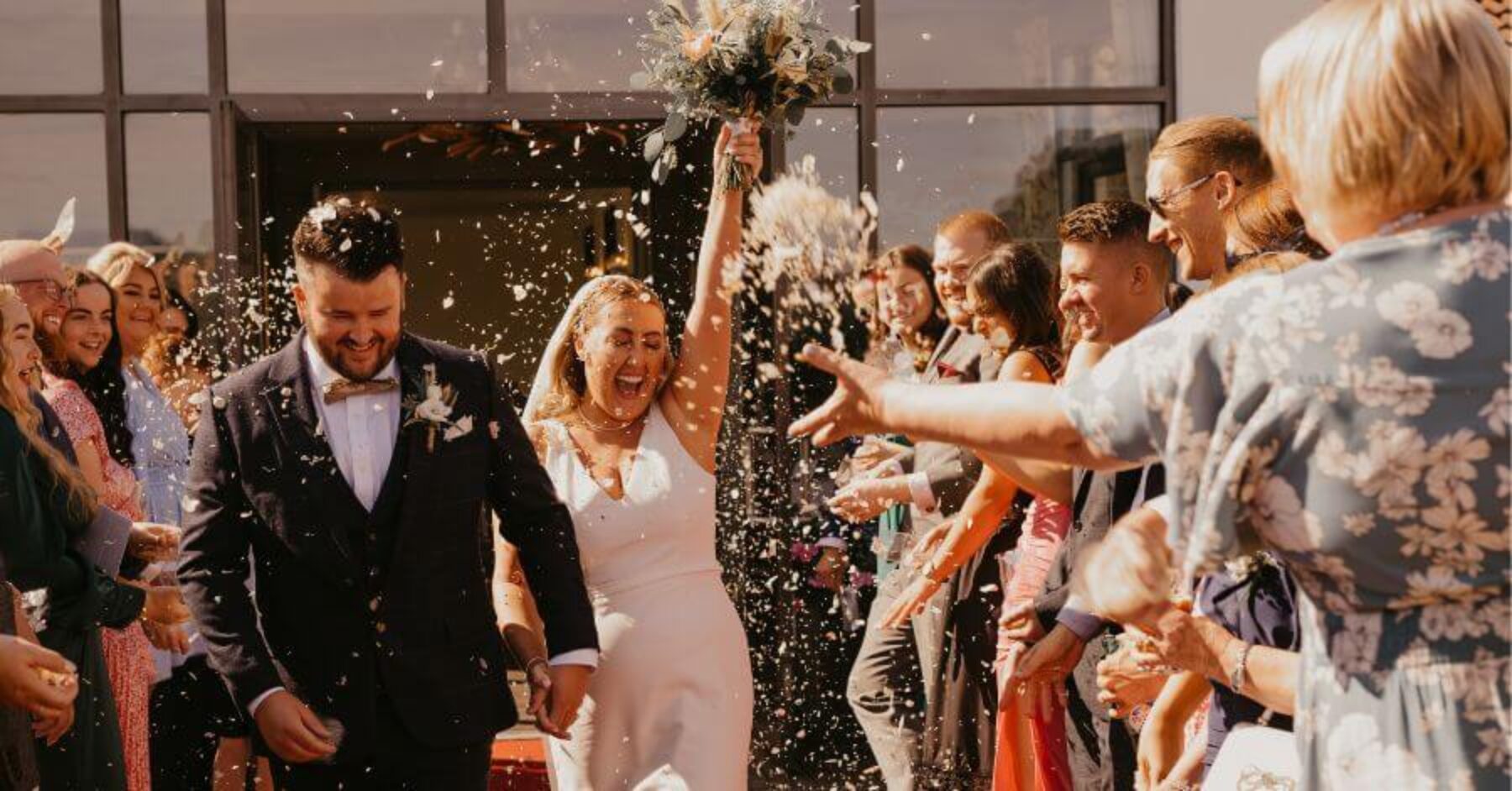 Bride and groom leaving the altar, celebrating with loved ones with confetti in the air.