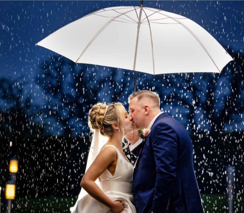 Stuart and Sian on their wedding evening, kissing in the rain under an umbrella