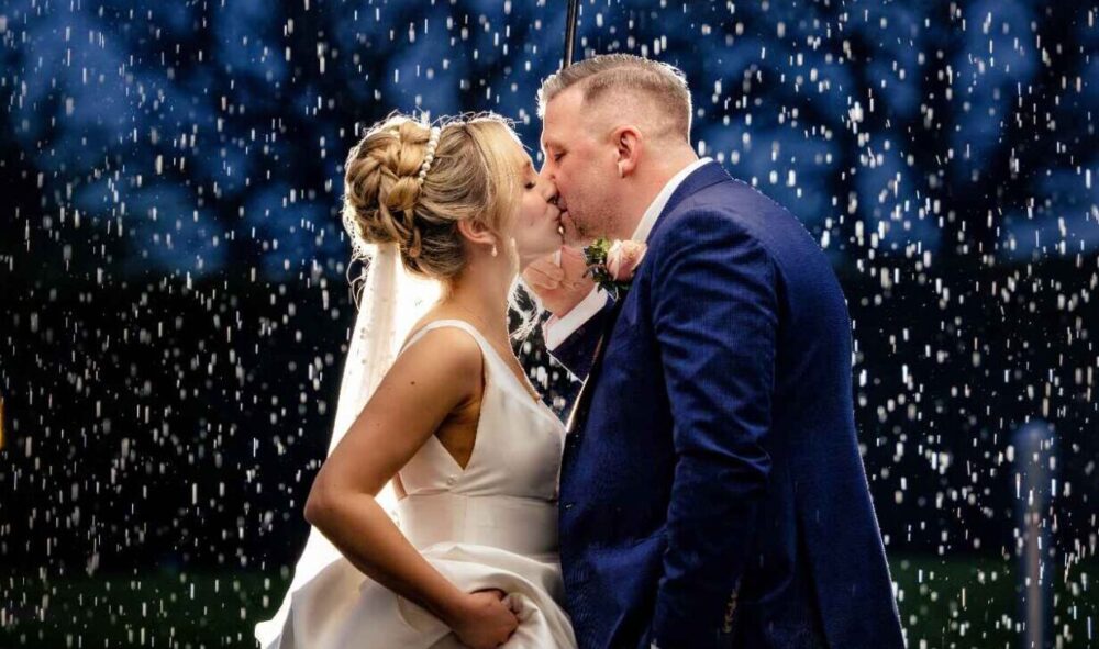 Stuart and Sian on their wedding evening, kissing in the rain under an umbrella