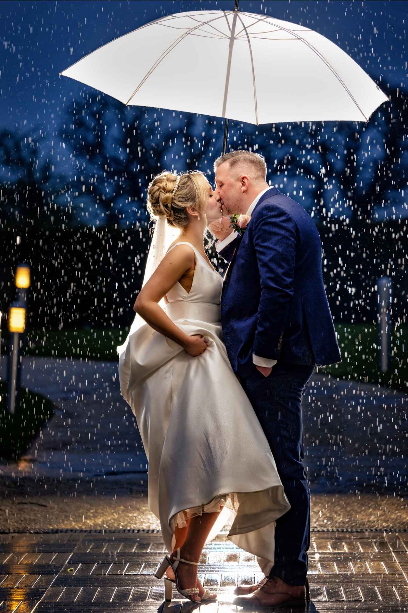 Stuart and Sian on their wedding evening, kissing in the rain under an umbrella