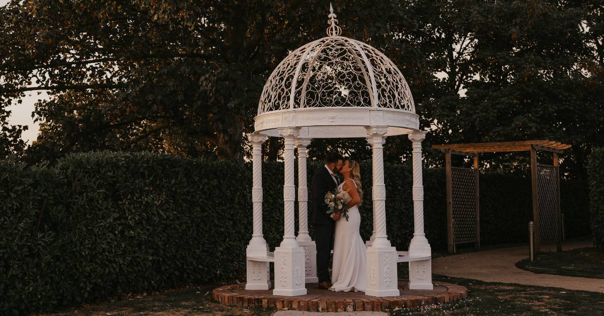 wedding couple kissing under a white gazebo