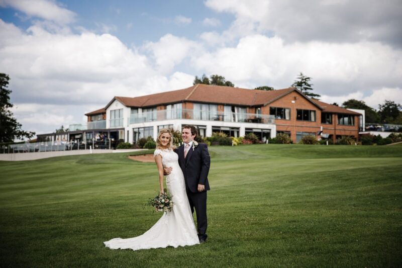 Newly-wed couple posing in front of wedding venue