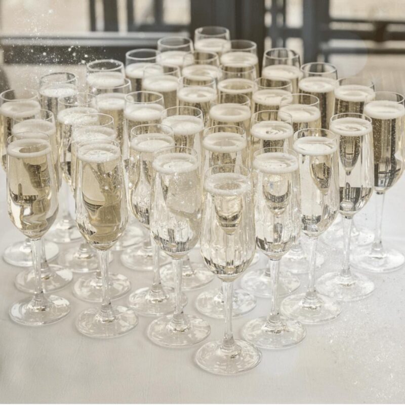 Close-up of a Prosecco glass with golden bubbles rising, set against a festive background with soft Christmas lights and seasonal decorations